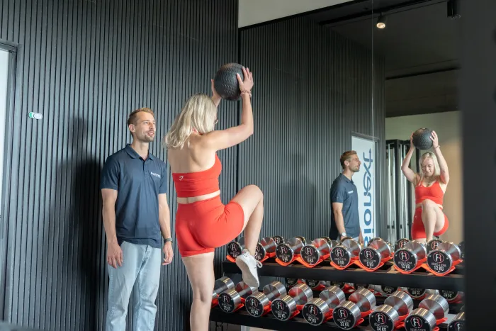 Sportster oefent met een medicijnbal terwijl een fysiotherapeut meekijkt