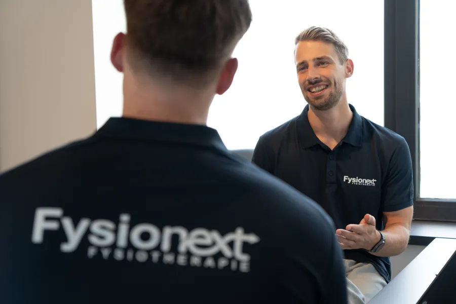 Twee fysiotherapeuten van FysioNext in gesprek tijdens een teamoverleg