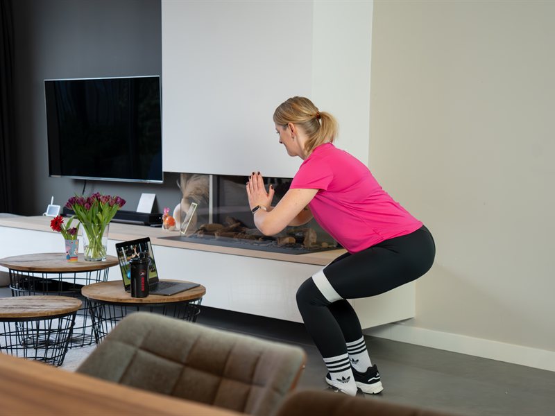 Vrouw voert een squat uit als kracht- en revalidatieoefening